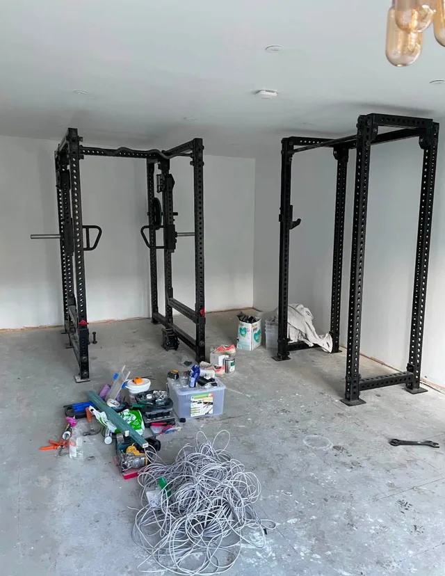Two Rogue racks being installed in Rob’s unfinished gym