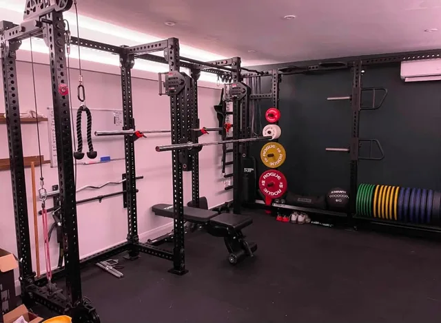Barbells and plates stored around the racks in Rob’s gym