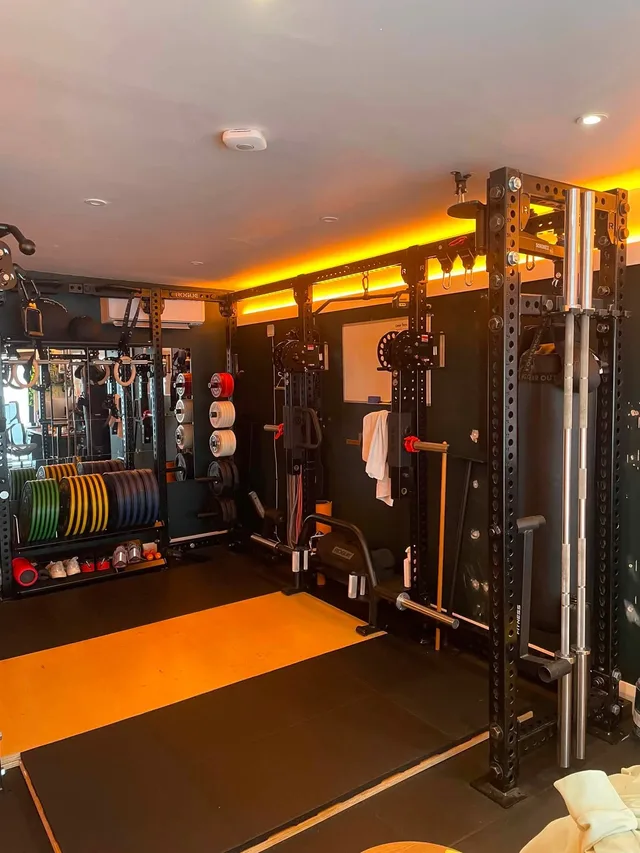 A weight bench beside the rack and lifting platform in Rob’s gym